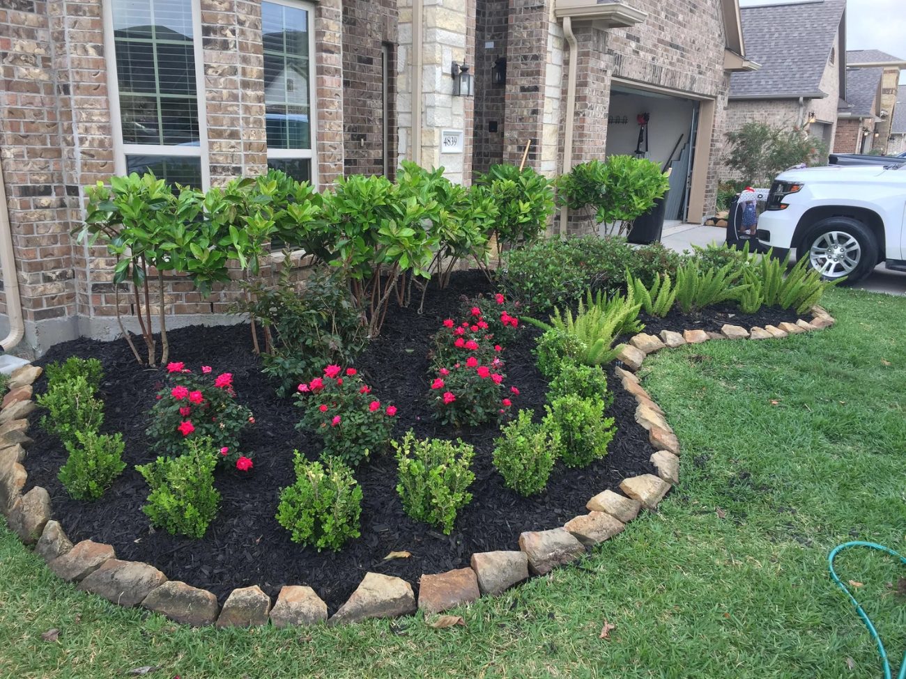 Flower bed with pink and red flowers and rock border