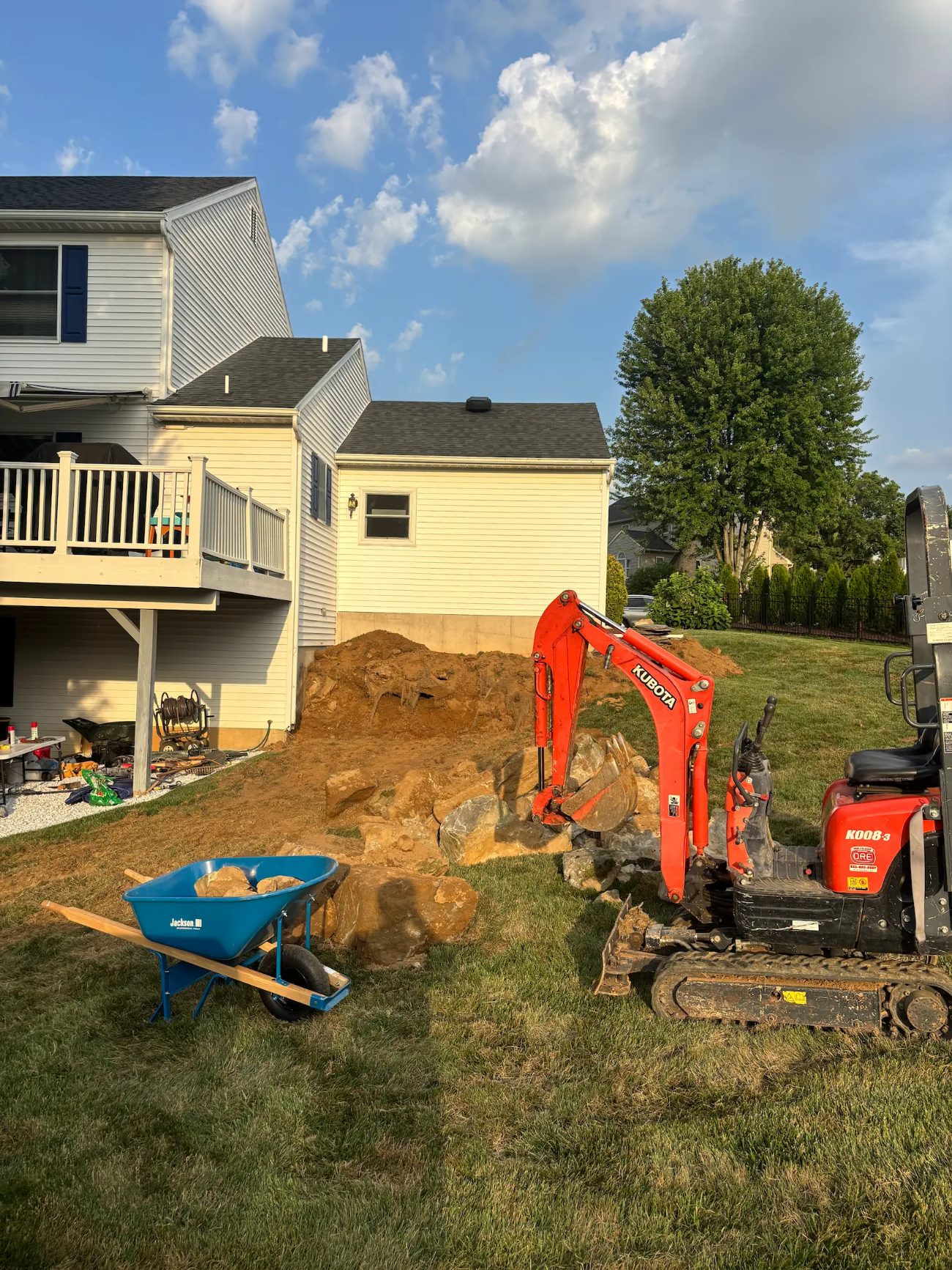 Mini excavator setting boulders for a backyard retaining project